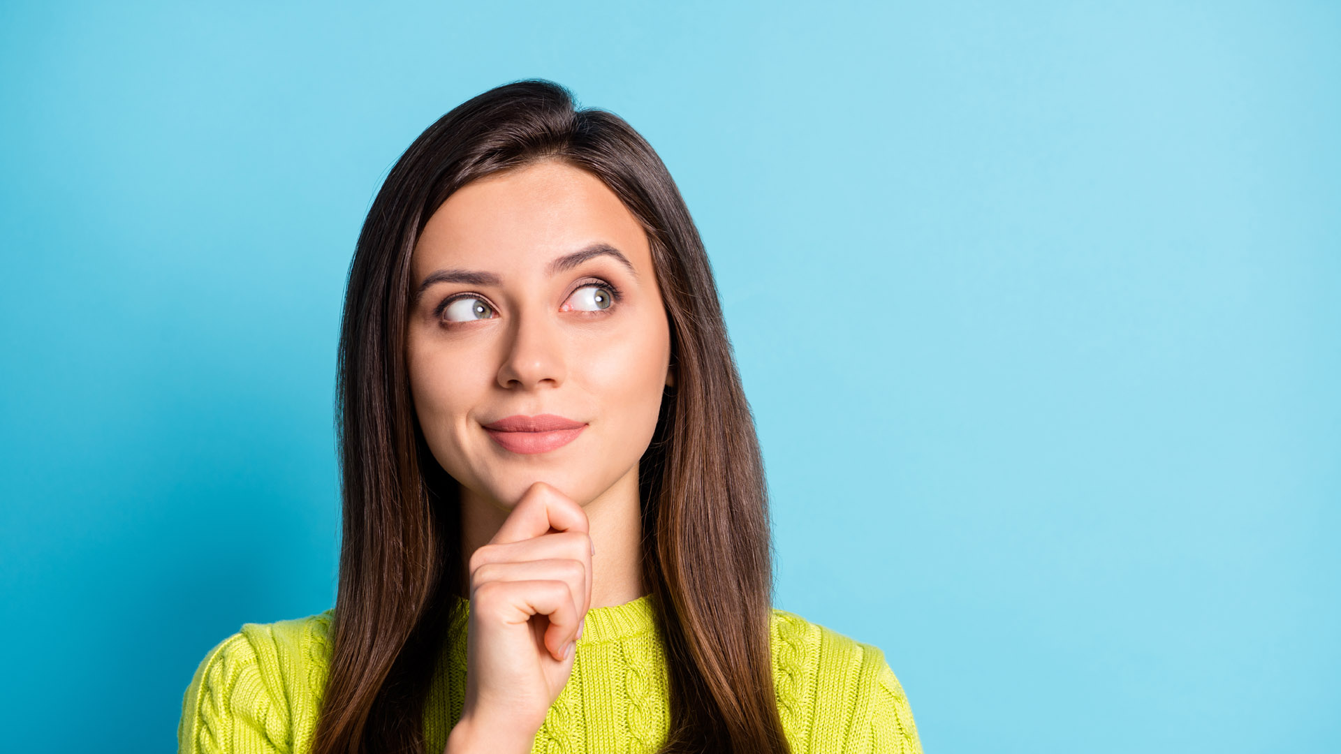 attractive girl standing in front of a blue wall thinking about strategy
